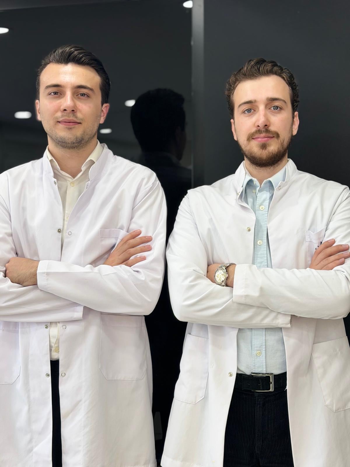 Dt. Fatih Samet Uslu (solda) ve Dt. İsmet Uslu beyaz önlükle, siyah fonda